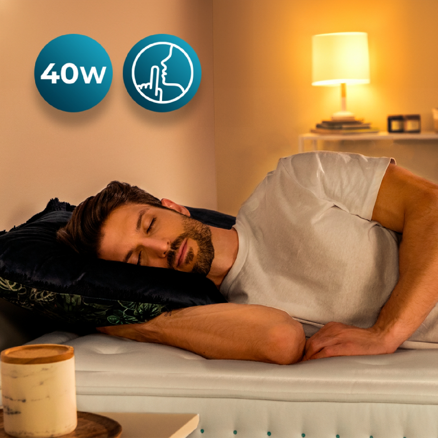 Hombre durmiendo plácidamente en un colchón. Iconos indican 40W y silencio.