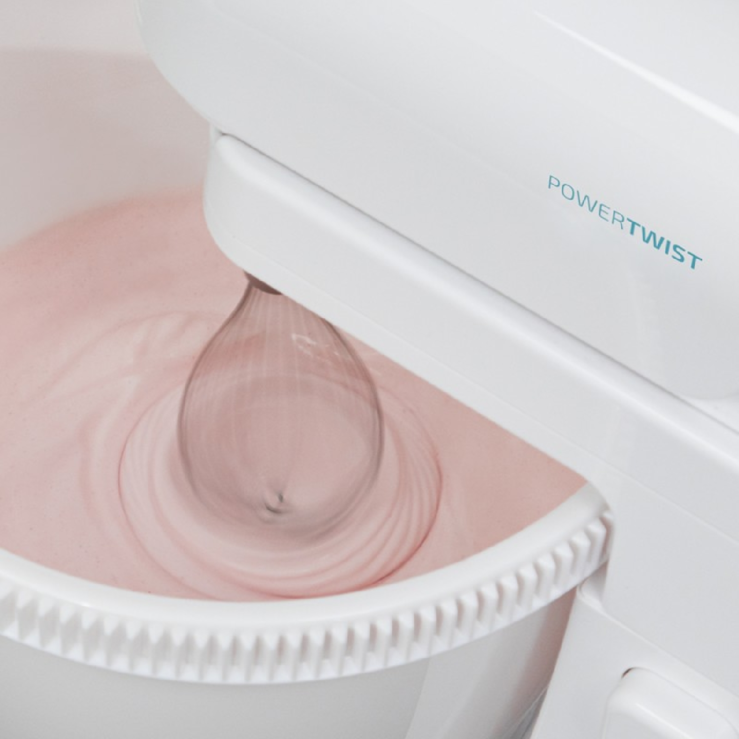 Una batidora de pie blanca mezcla una masa rosa en un bol blanco.