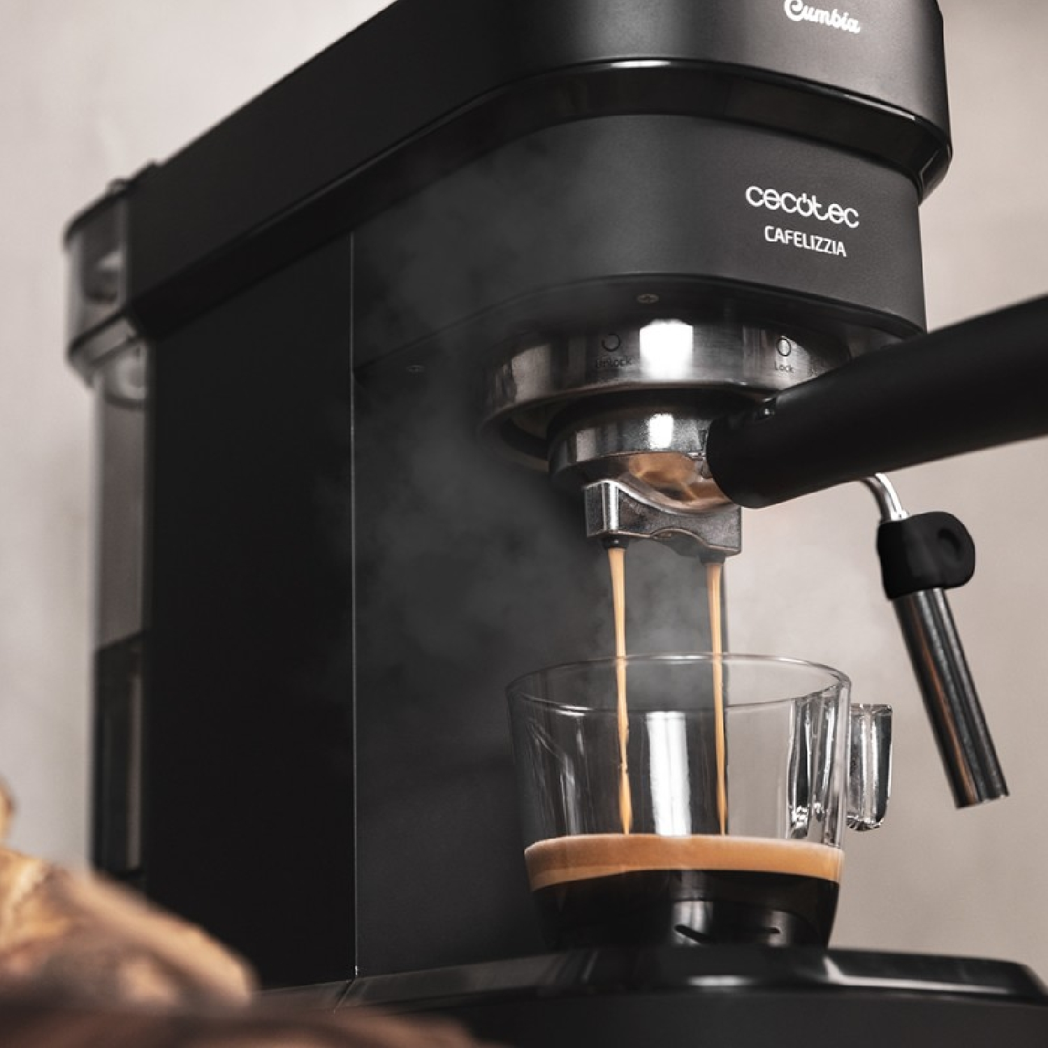 Czarny ekspres do kawy parzy kawę do szklanki do espresso, unosi się para.