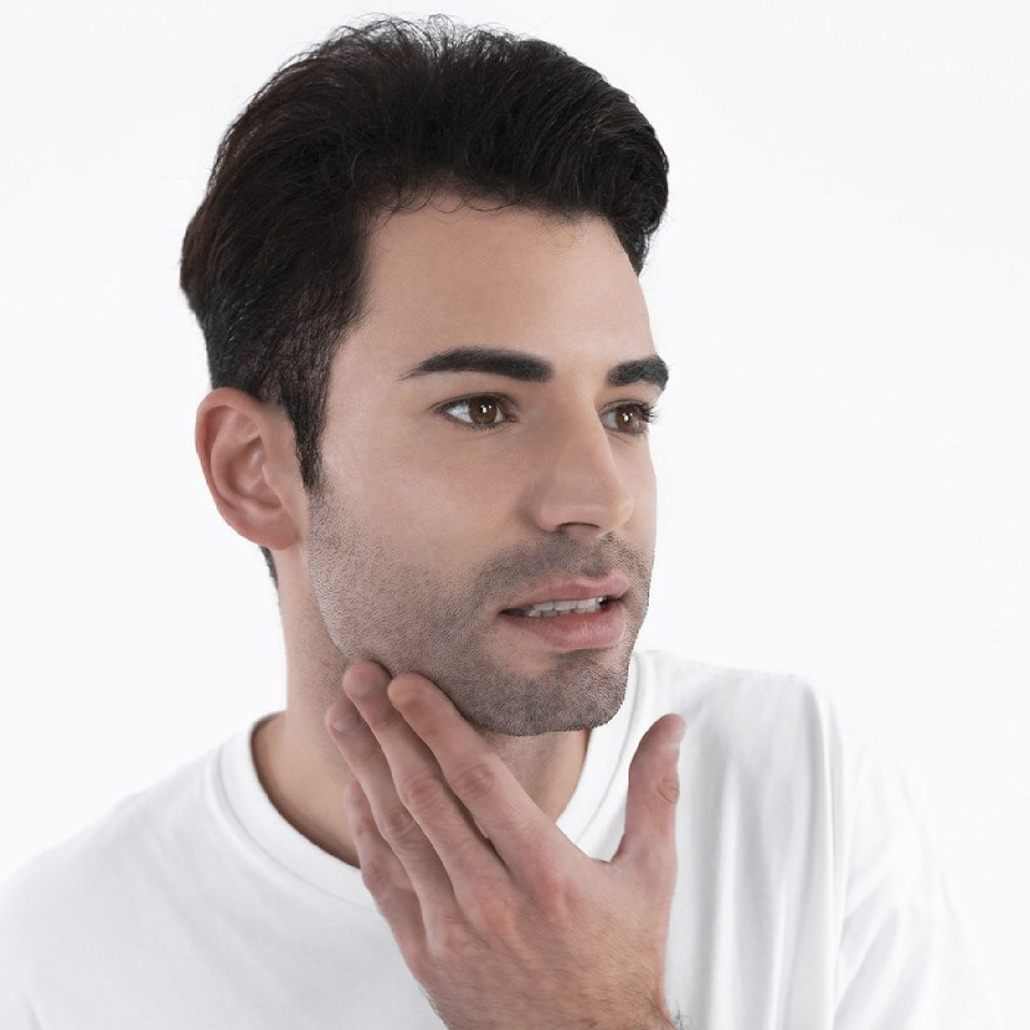 Hombre de pelo oscuro se toca la barbilla. Viste una camiseta blanca.