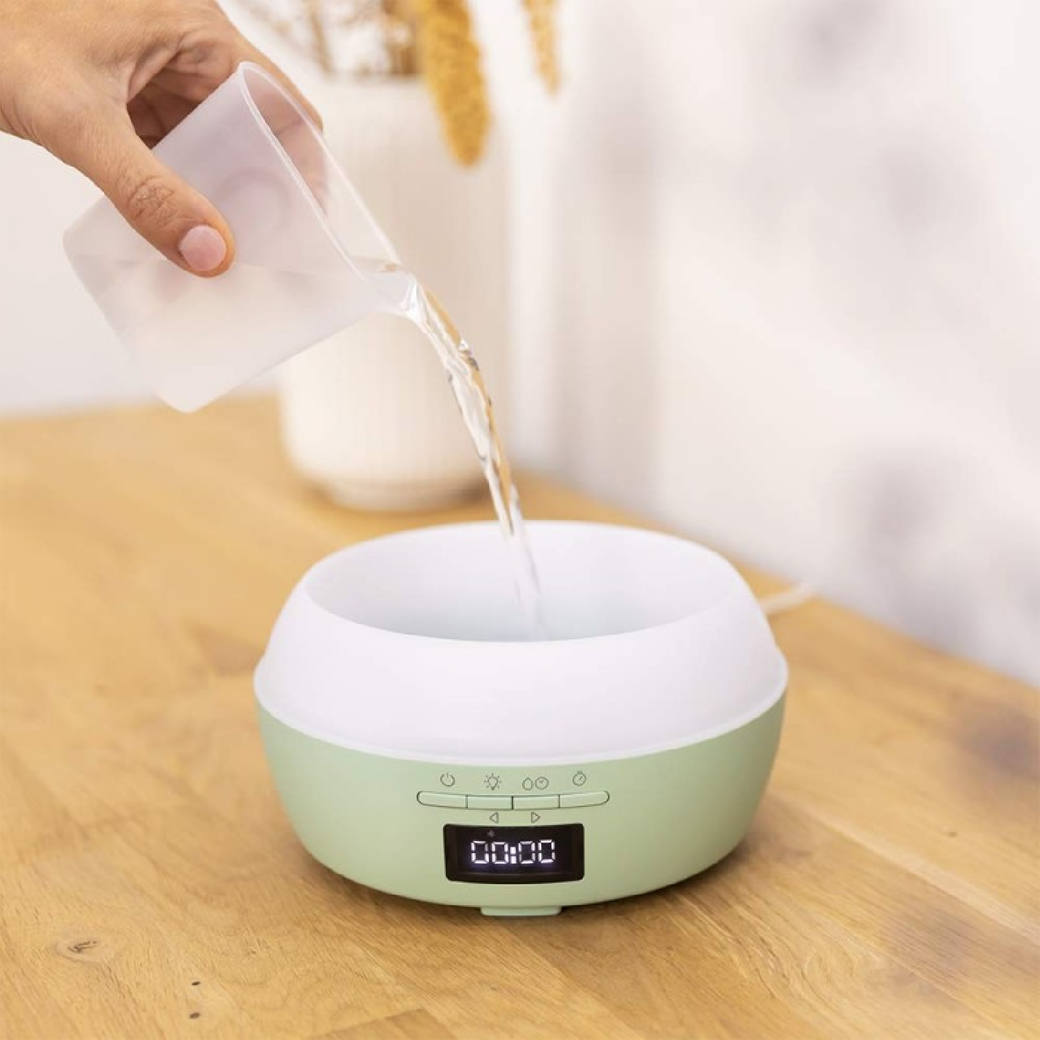 Wasser wird aus einem Becher in einen hellgrünen Diffusor gegossen.