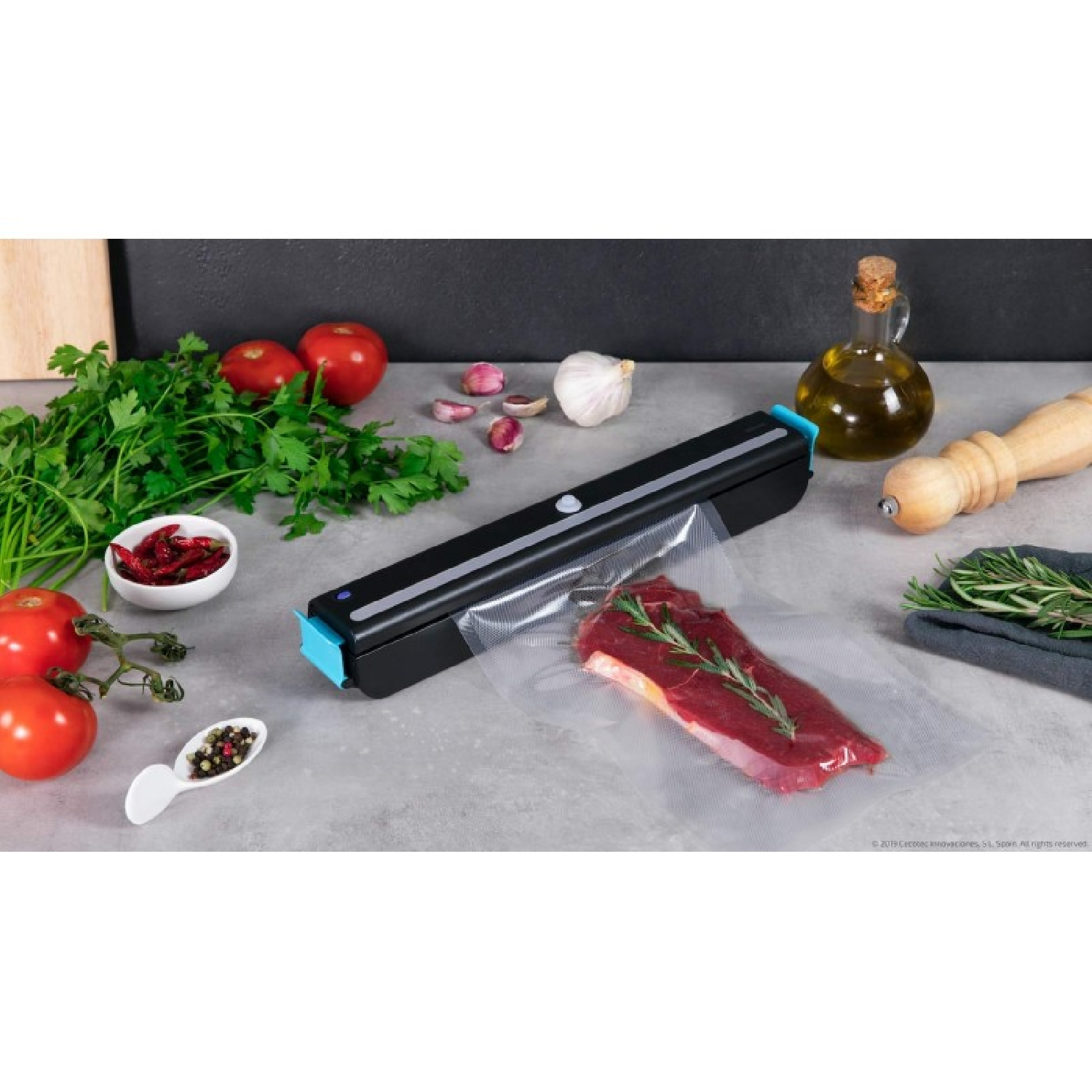 Una máquina selladora al vacío sella un trozo de carne con romero en una bolsa de plástico. Al lado hay tomates, ajo y hierbas.