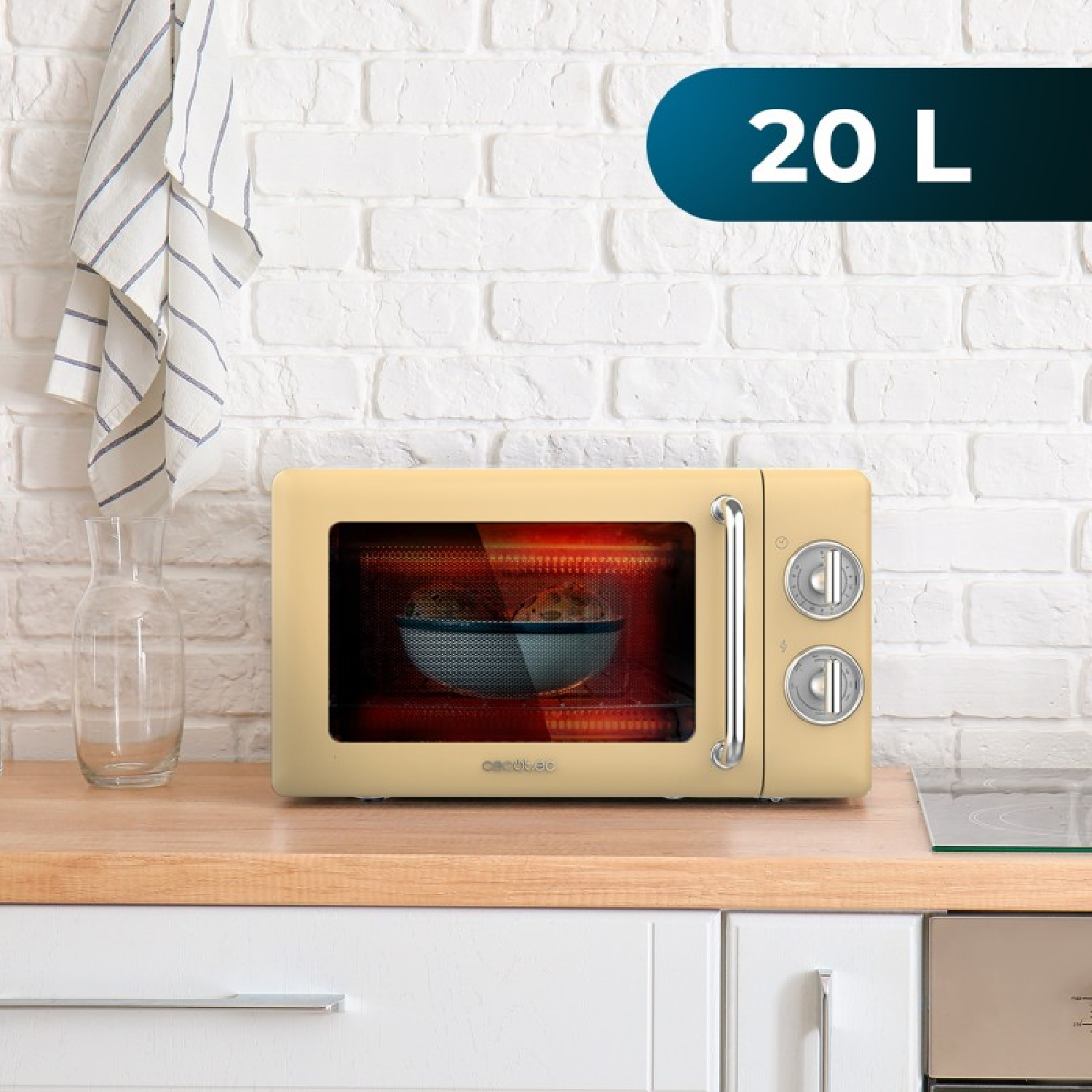 Kremowa kuchenka mikrofalowa o pojemności 20L stoi na blacie obok dzbanka.