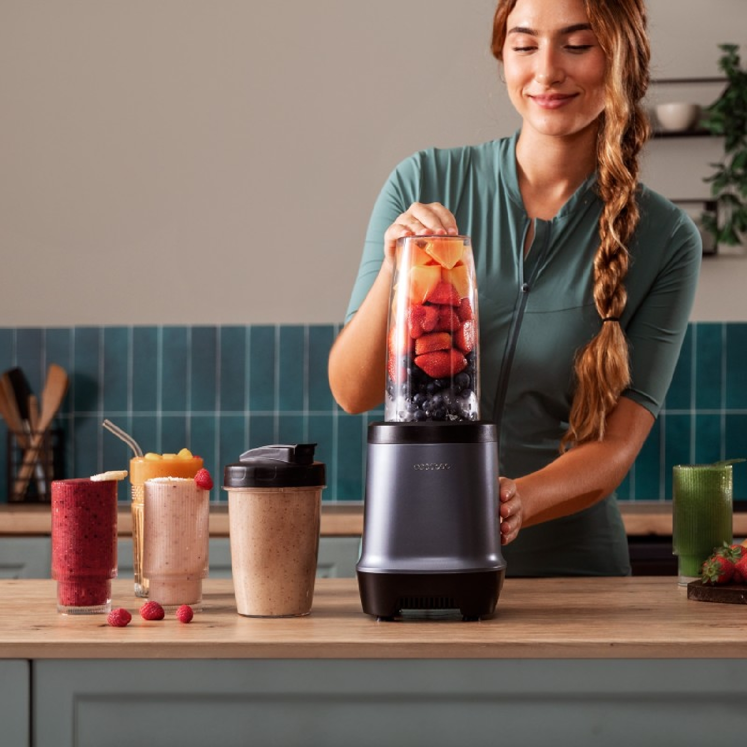 Mujer preparando batido de frutas en licuadora. Varias bebidas de frutas en el mostrador.