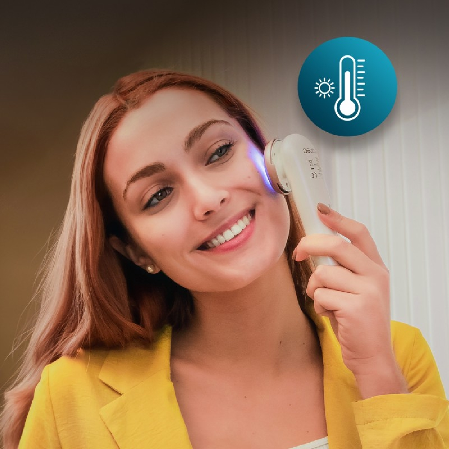 Mujer con chaqueta amarilla usa dispositivo de cuidado de la piel con luz azul e icono de termómetro.