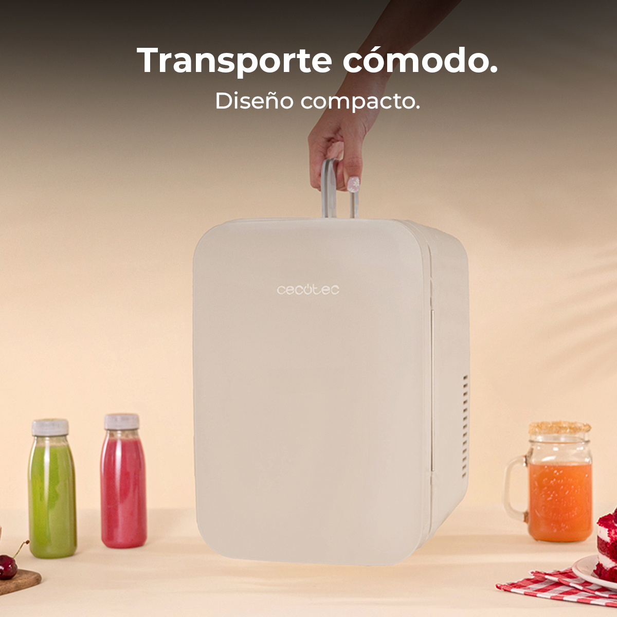 Un mini frigorifero bianco è tenuto per mano dal suo manico. Vicino ci sono bottiglie di succo e un bicchiere di succo.