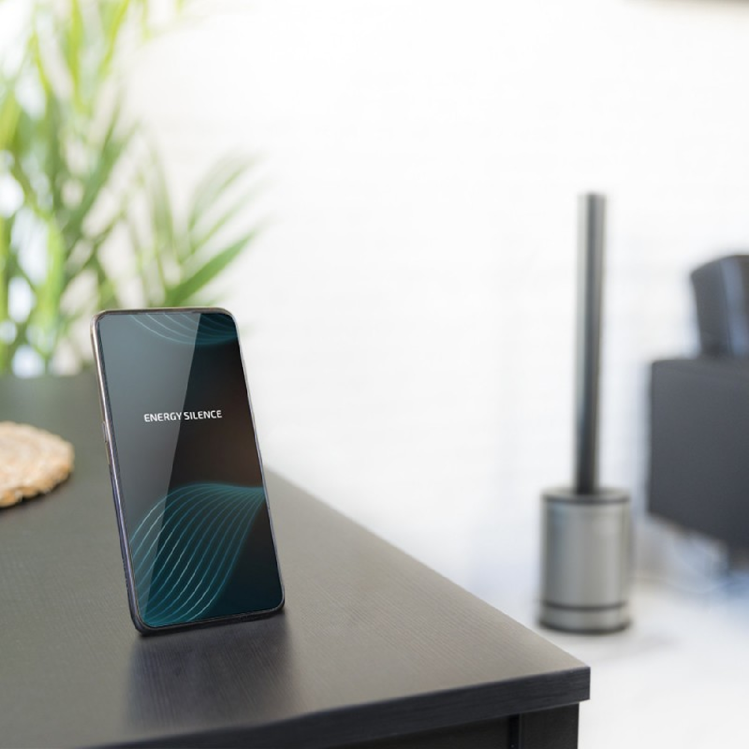 Uno smartphone con "ENERGY SILENCE" su un tavolo nero.