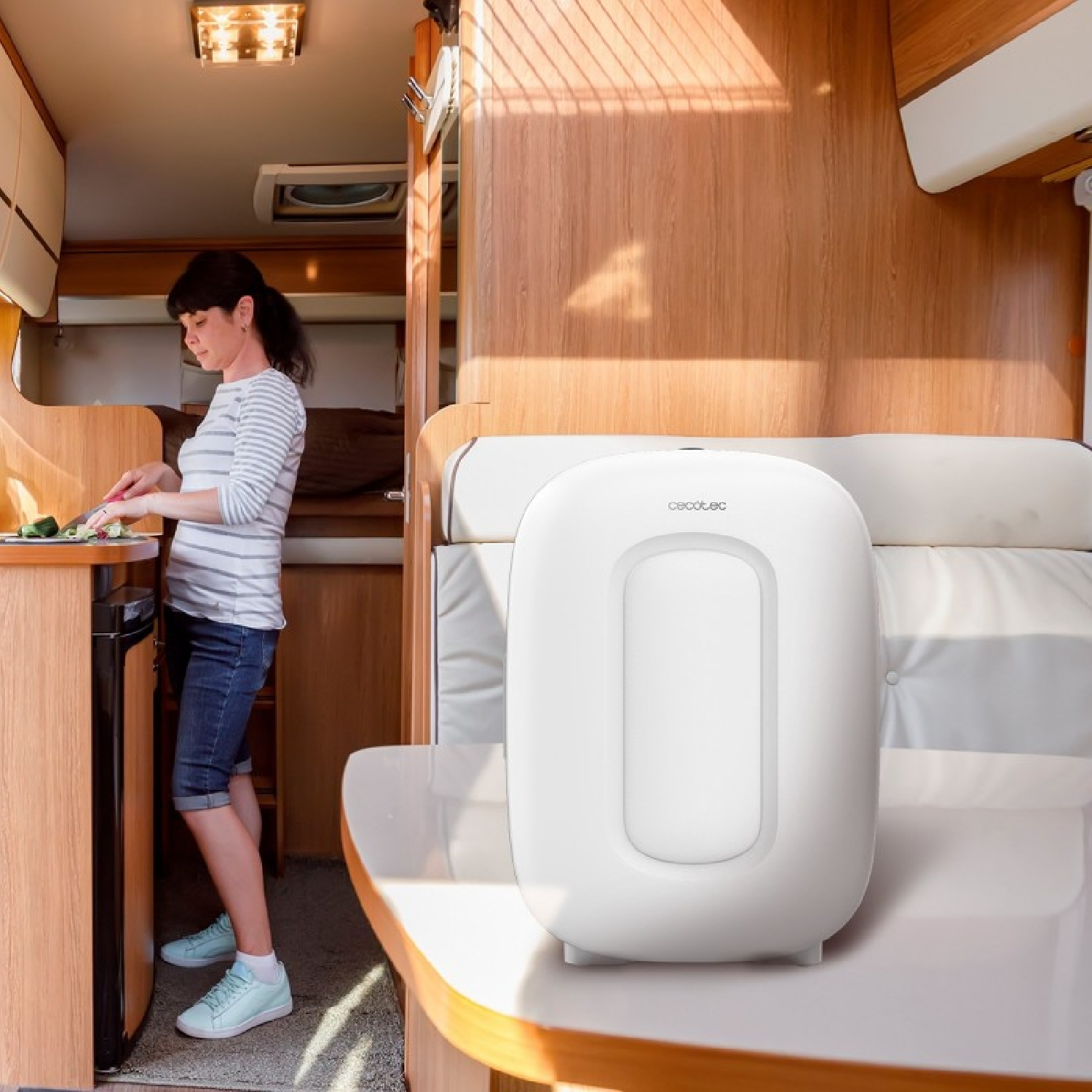 Una mujer corta verduras en la cocina de una autocaravana. Un aparato blanco sobre el mostrador.