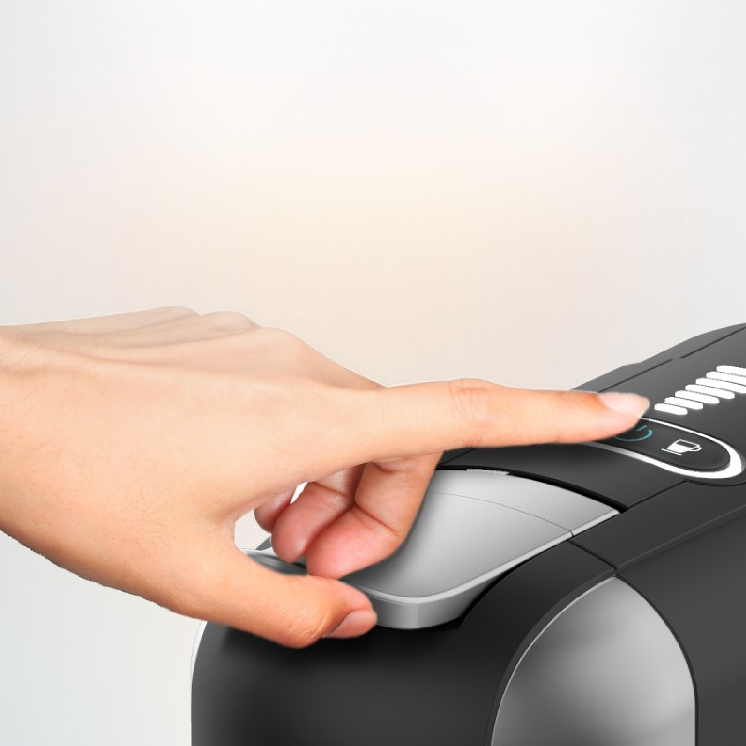 Een hand drukt op een knop van een zwarte koffiemachine.