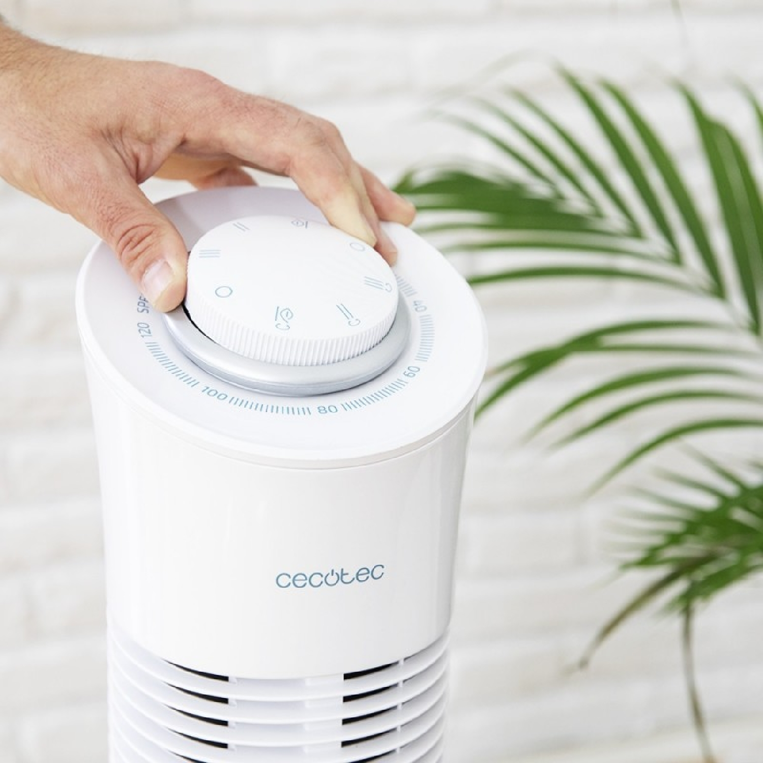 A hand turning a white fan with a dial and symbols.