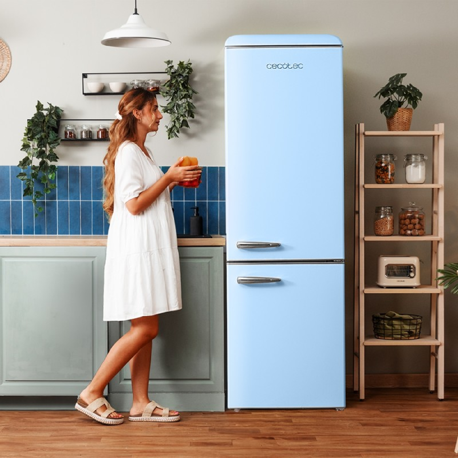 Mujer con vestido blanco sosteniendo fruta junto a un frigorífico retro azul claro.