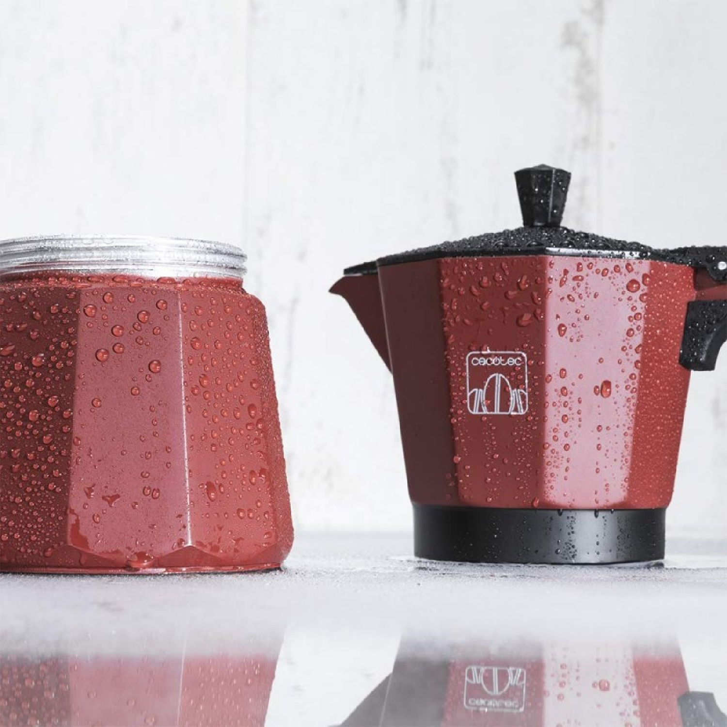 Caffettiera rossa e barattolo di vetro coperti di gocce d'acqua su un tavolo.