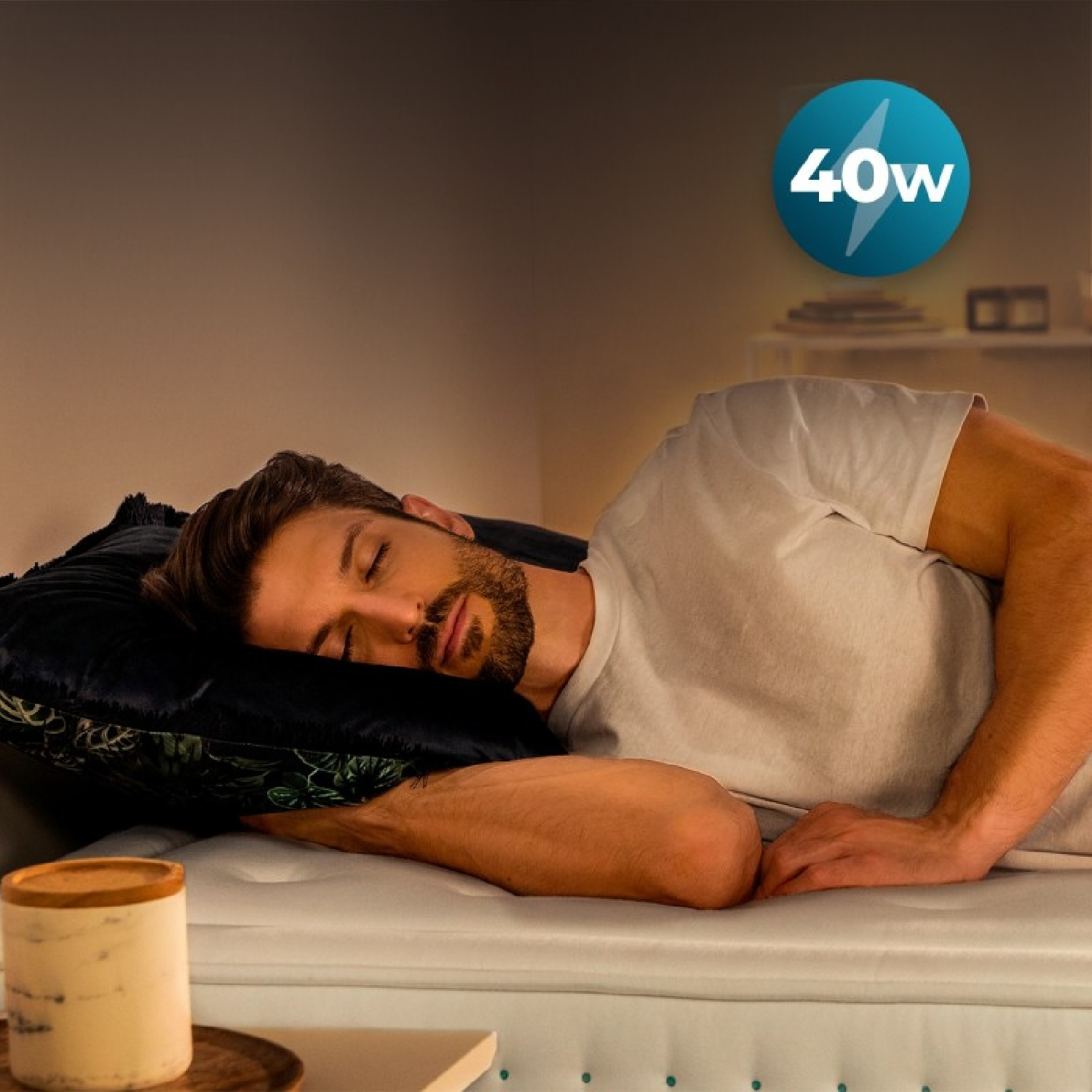 Uomo che dorme su un letto, con cuscino e candela vicini. Logo 40w in alto a destra.