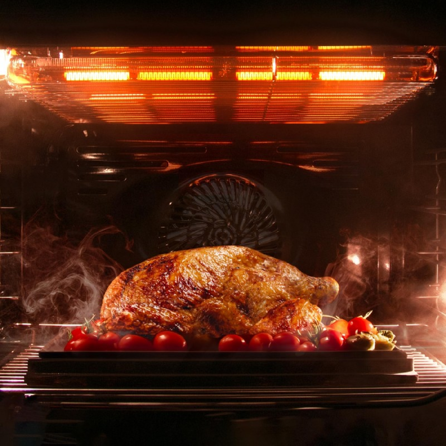 Un pollo asado dorado con tomates se cocina en un horno caliente.