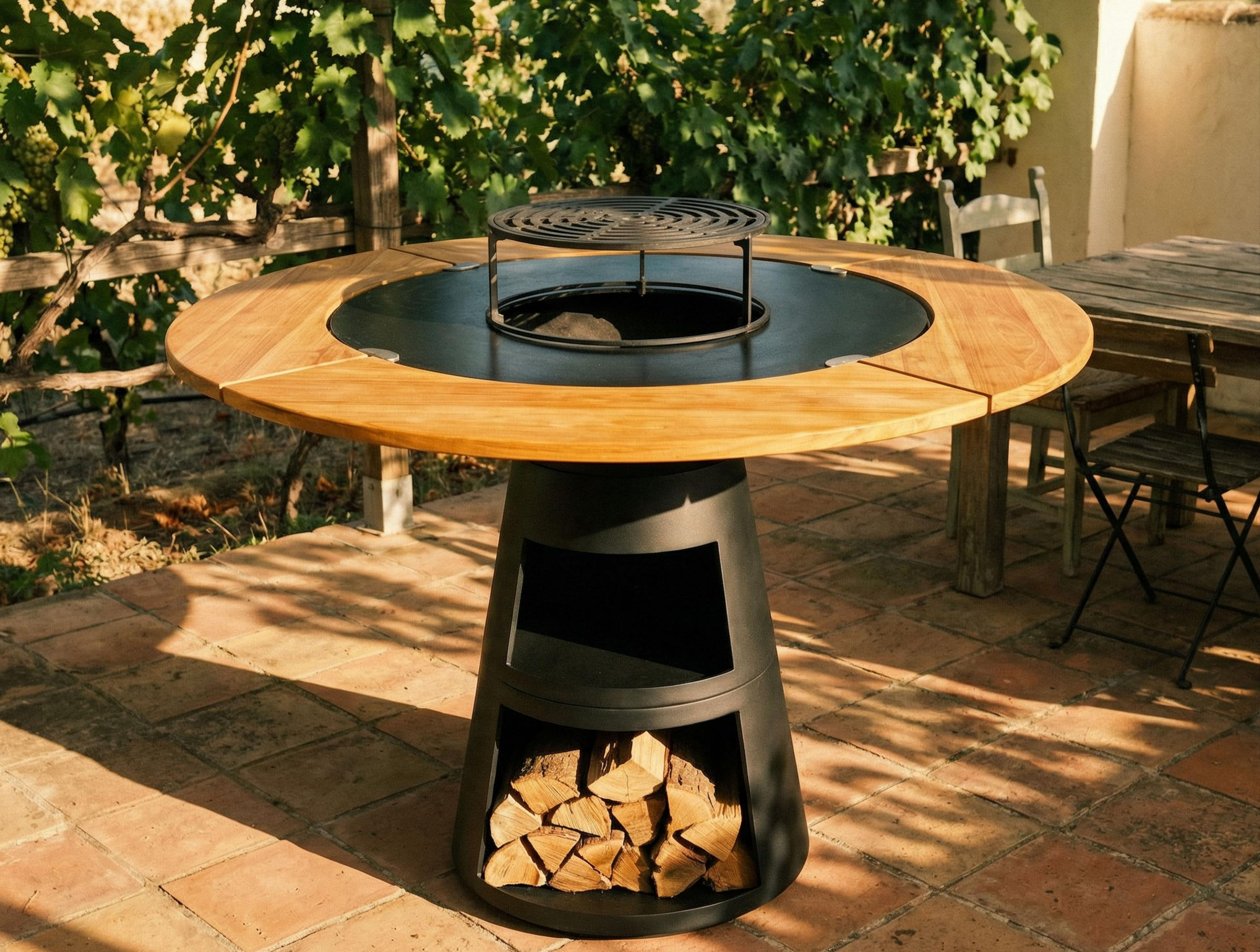 Runder Holztisch mit integriertem Grill auf schwarzem Sockel, gefüllt mit Holz.