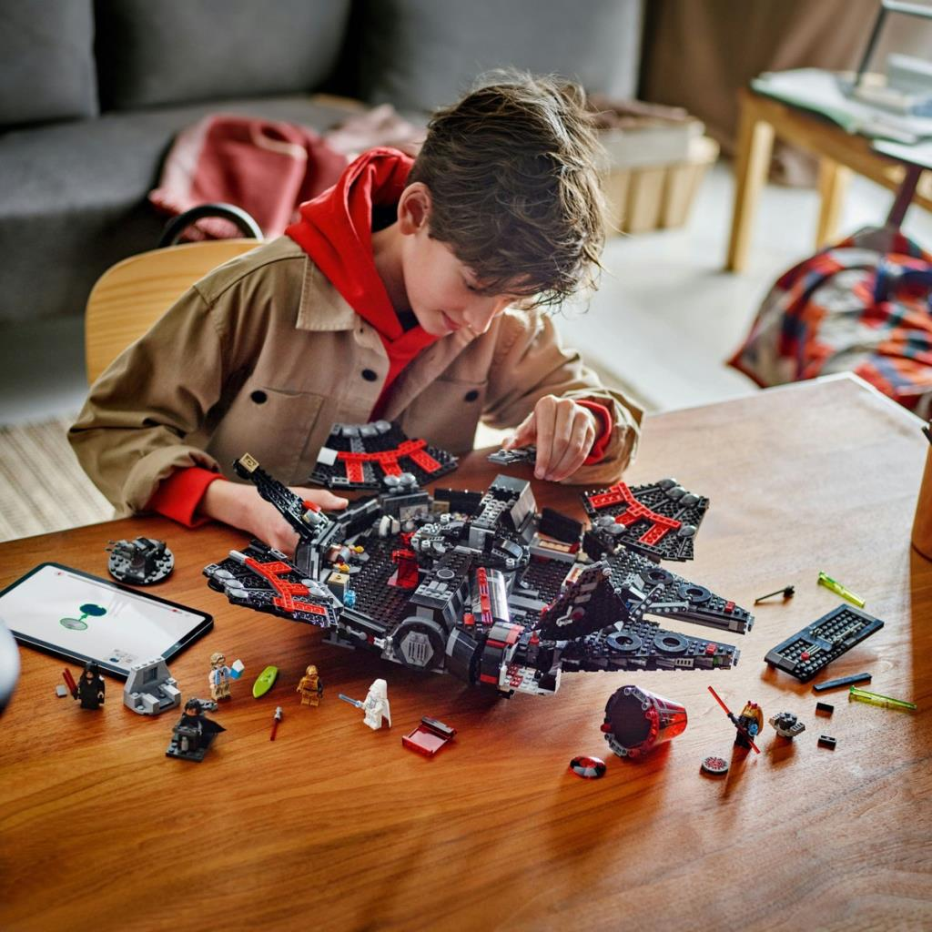 Çocuk ahşap bir masada Lego parçalarından siyah bir uzay gemisi yapıyor.