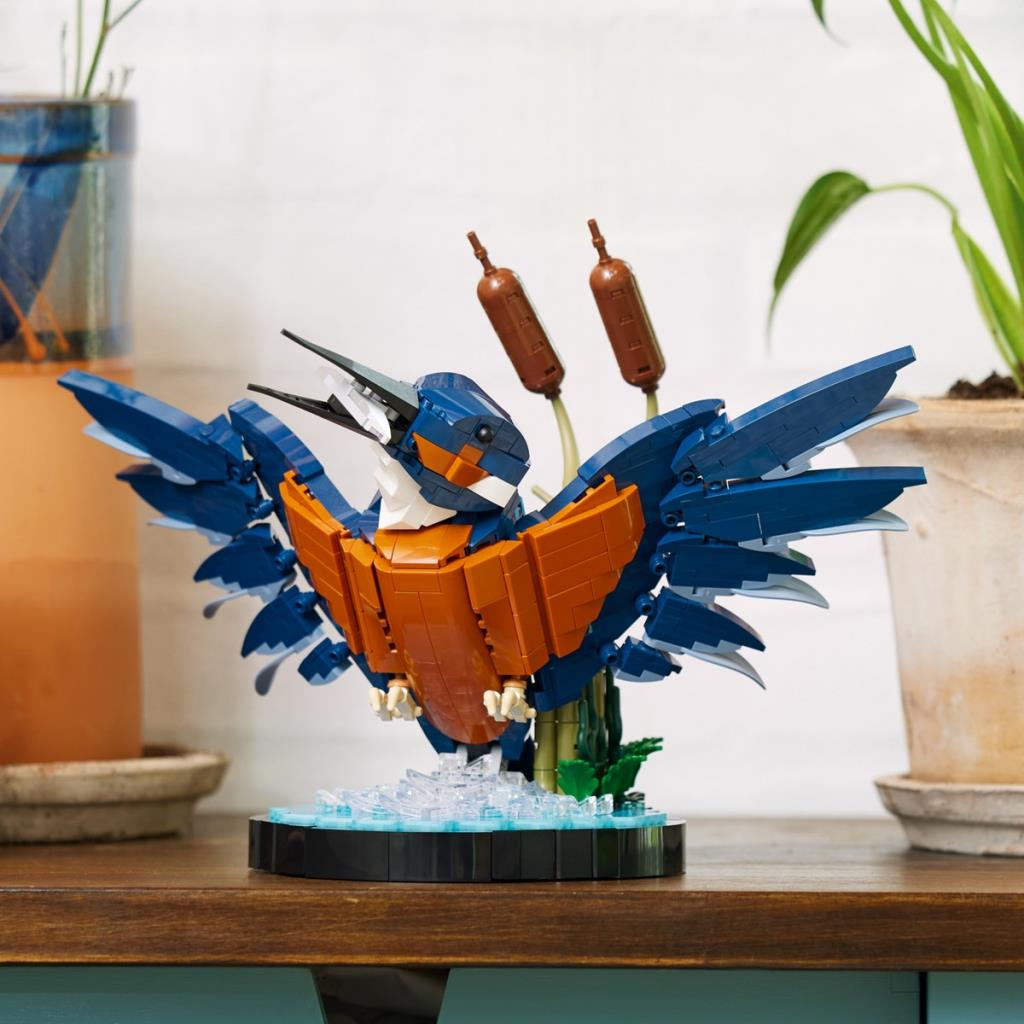 Kanatları açık, mavi ve turuncu Lego kuş, su tabanı üzerinde duruyor.