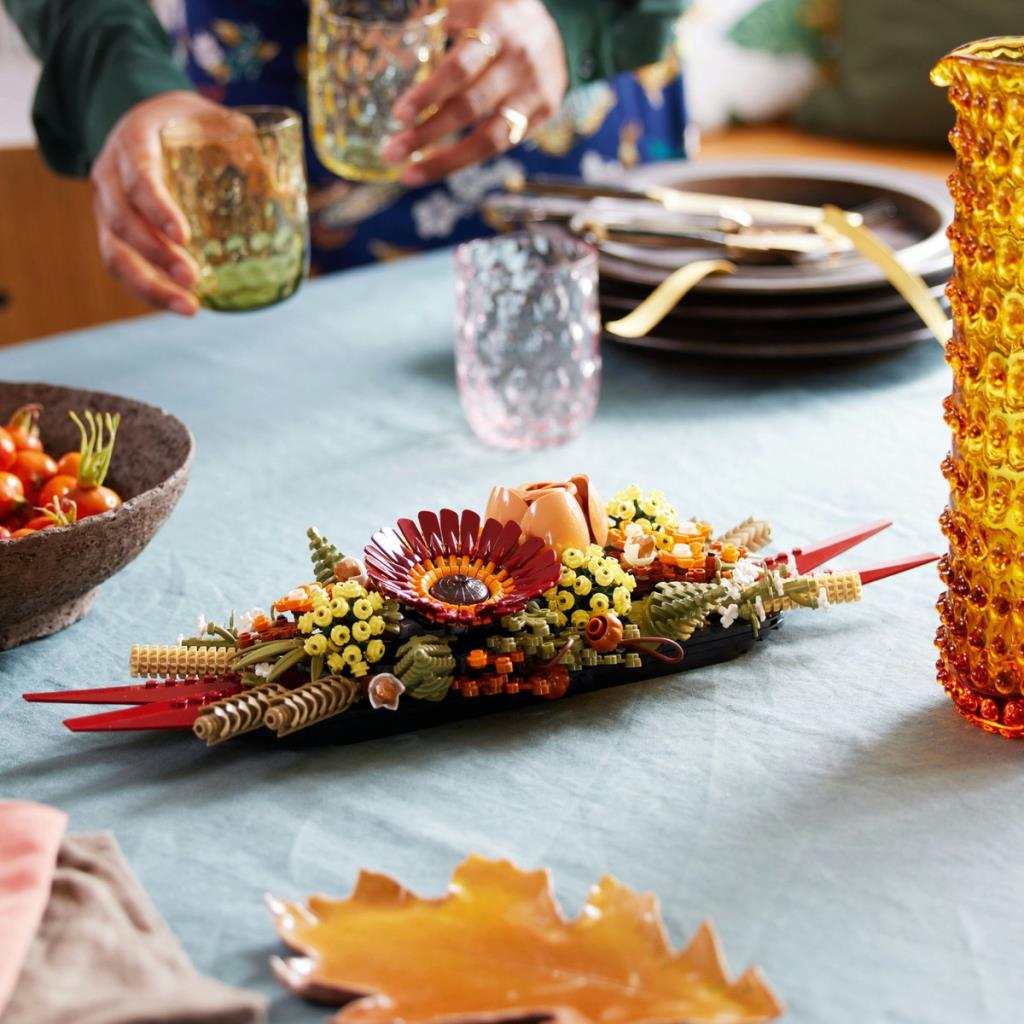 Un arrangement floral Lego avec des fleurs rouges et jaunes sur une table.