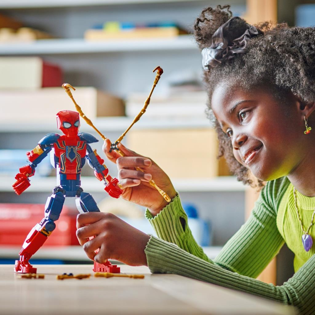 Ein Mädchen spielt mit einer rot-blauen Spiderman-Figur aus Lego.