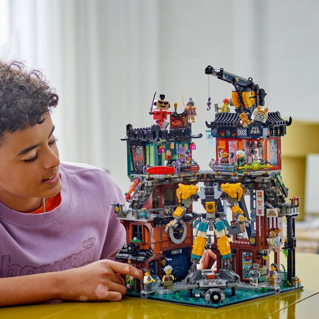 Bir çocuk robotlu detaylı bir Japon binası Lego setine bakıyor.