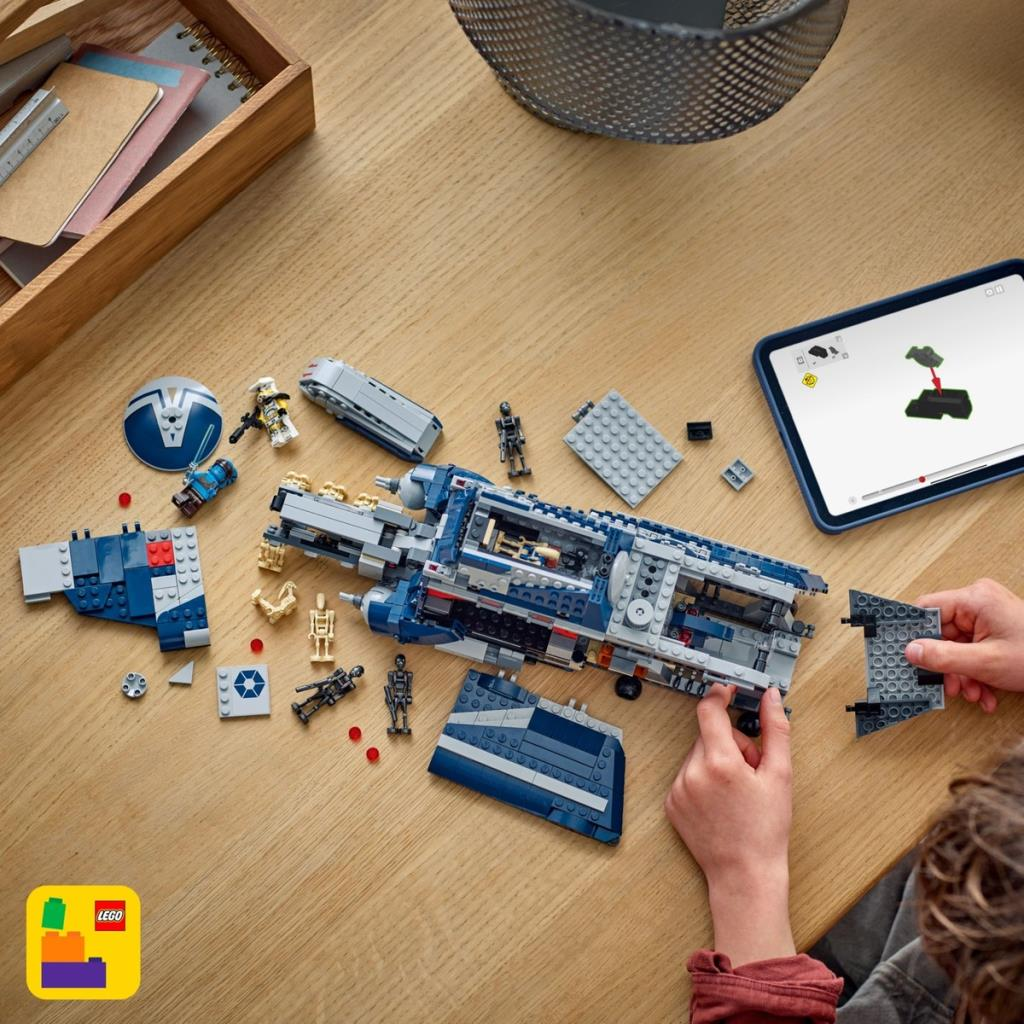 Un niño arma un set de nave espacial Lego azul y gris sobre una mesa de madera.