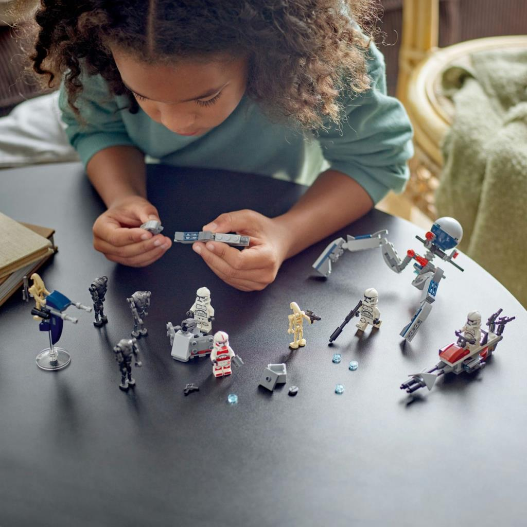 Bir çocuk siyah bir masada Star Wars Lego figürleri ve araçları inşa ediyor.