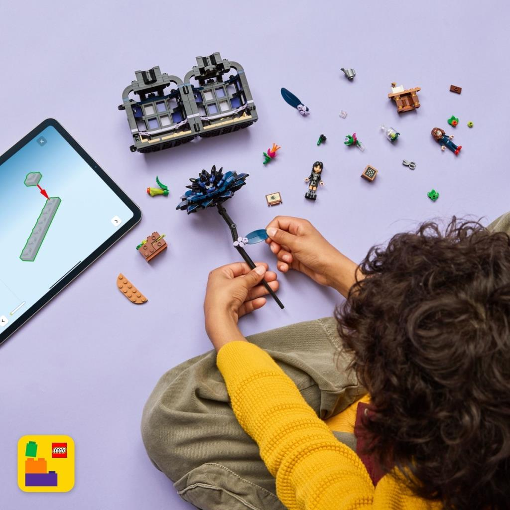 Çocuk LEGO tuğlaları ve tablet ile inşa ediyor. Siyah bir çiçek odak noktasında.