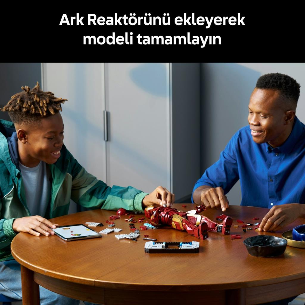 Adam ve çocuk ahşap masada Lego Iron Man yapıyor.