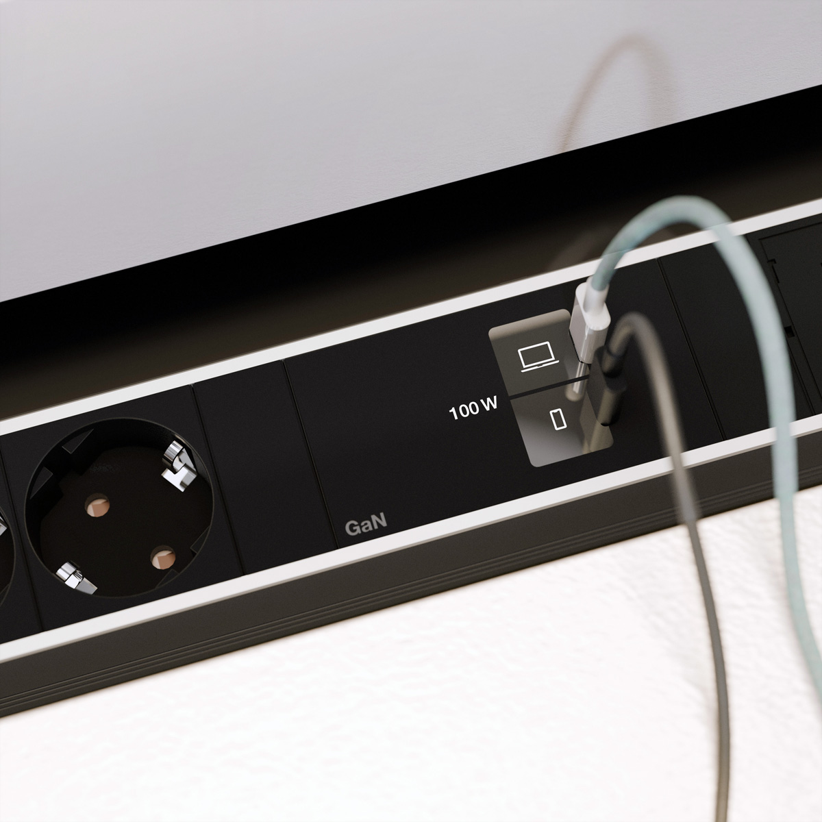 Schwarze Steckdosenleiste mit zwei Steckdosen und USB-Anschlüssen. Ein Kabel ist angeschlossen.