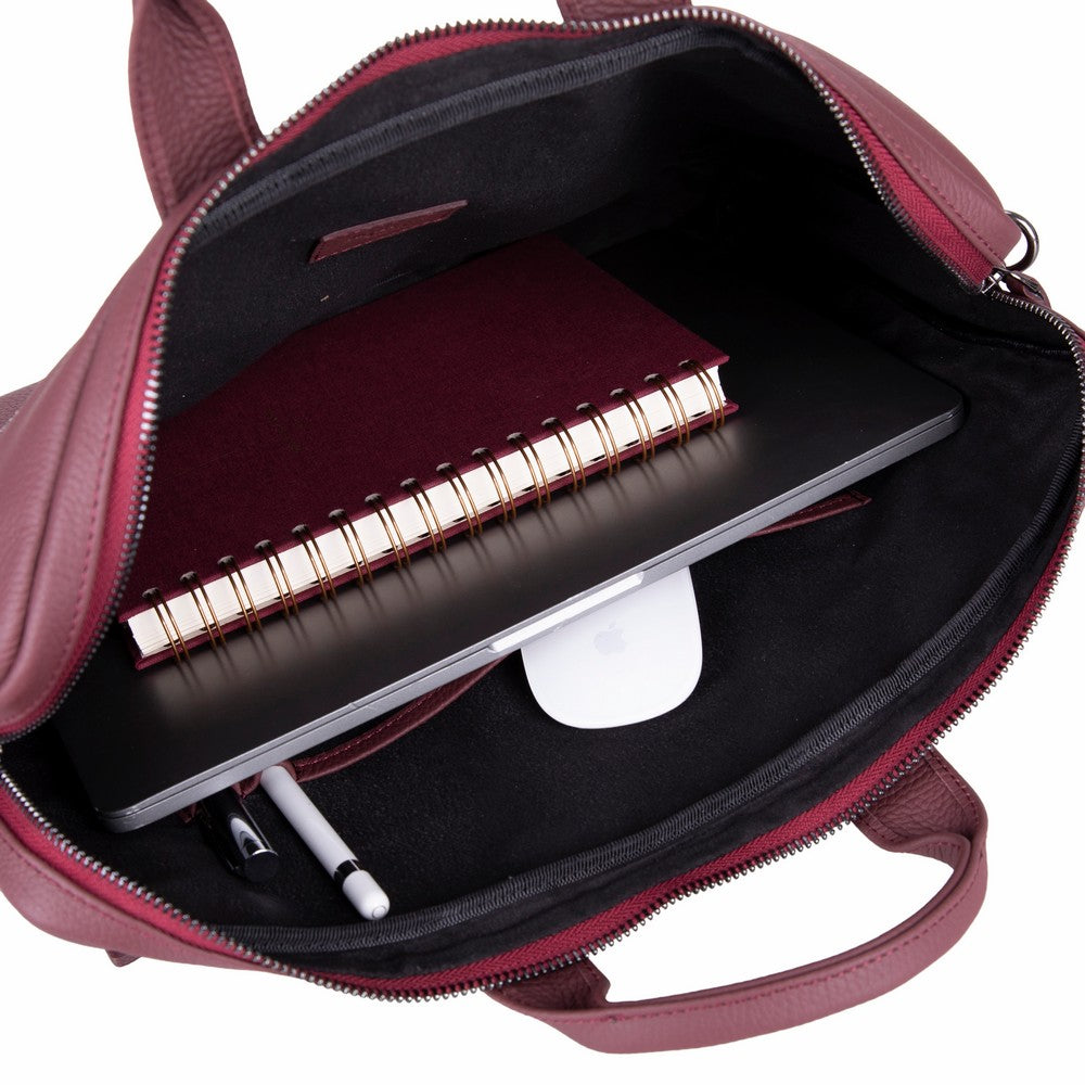 Laptop, defter, fare ve kalem bulunan açık bordo deri çanta.