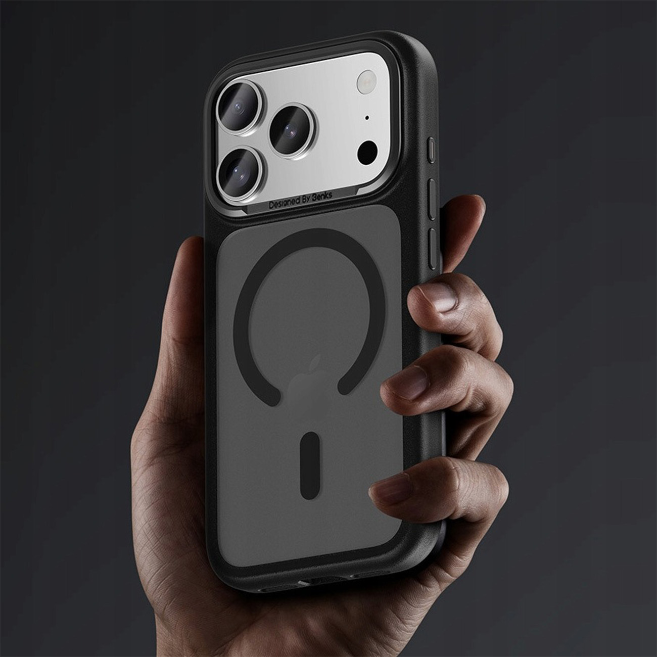 Una mano sostiene una funda de teléfono negra con tres cámaras y un anillo magnético.