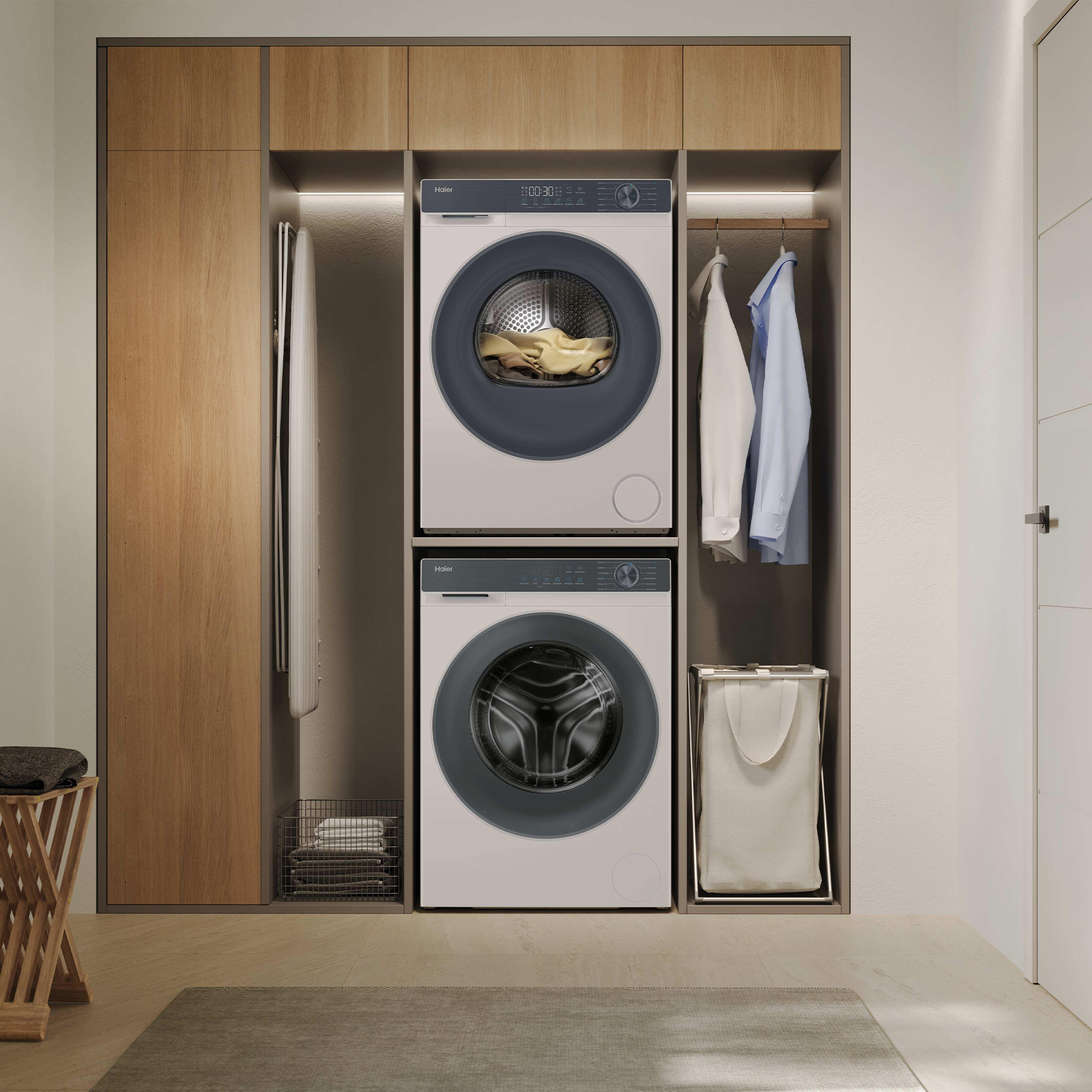 Zwei Haier-Waschmaschinen, Wäschekorb, Bügelbrett und Kleidung in einem Schrank.