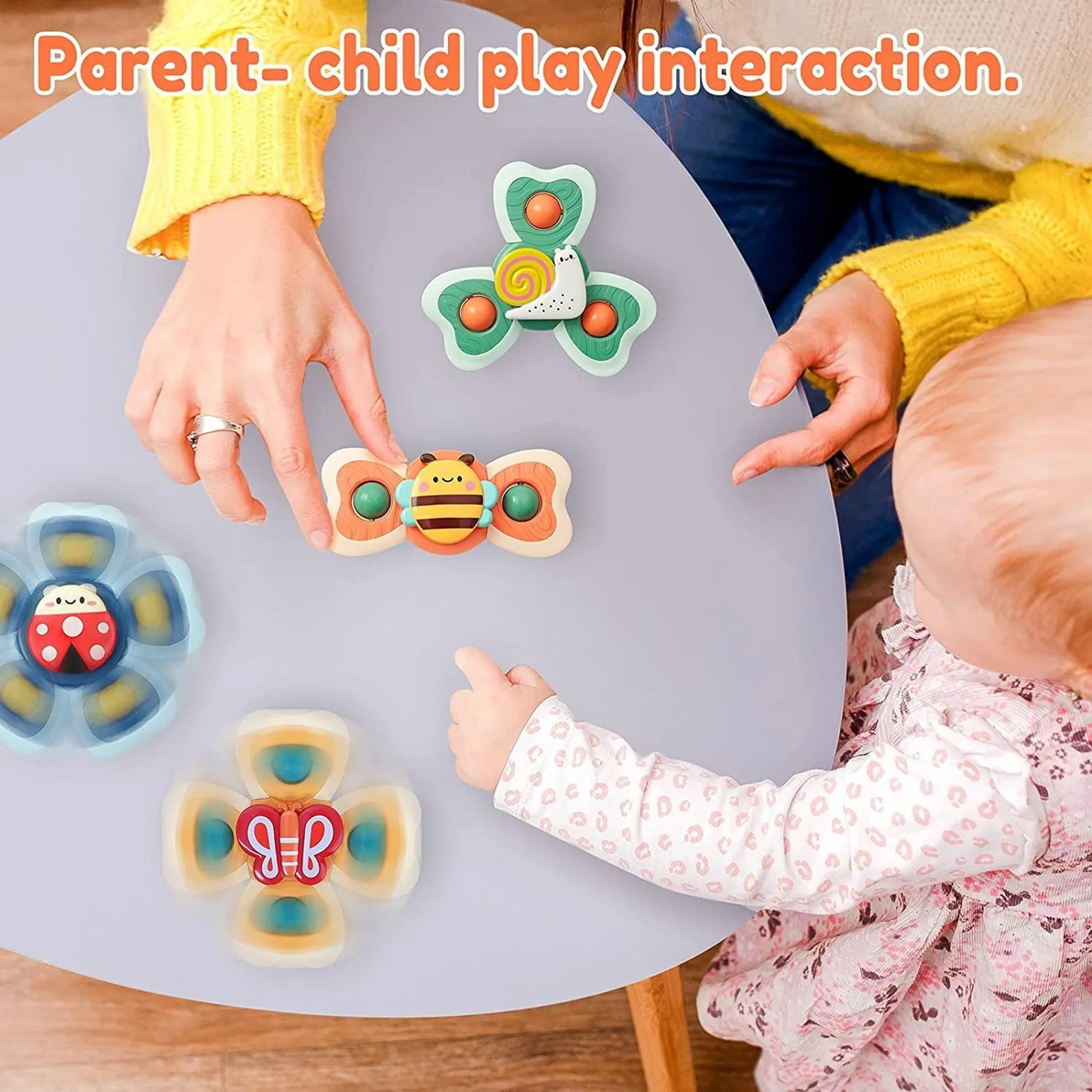 Ein Baby und eine Erwachsene spielen mit bunten Spielzeug-Spinnern auf einem Tisch.