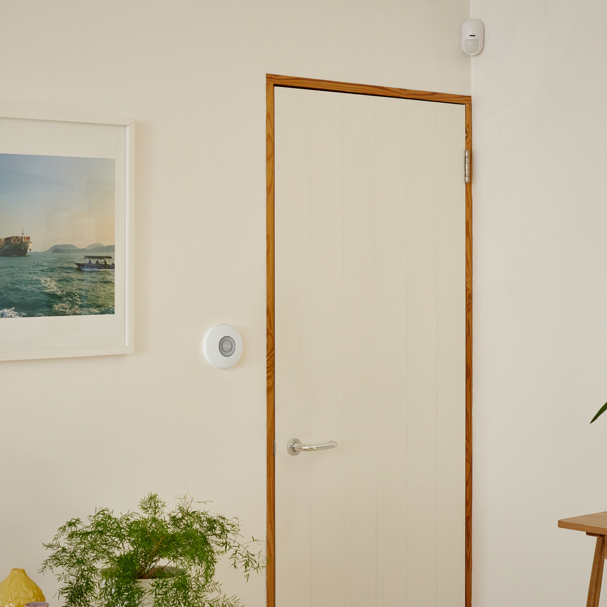 Une poignée de porte blanche sur une porte crème à cadre en bois. Un mur blanc à côté.