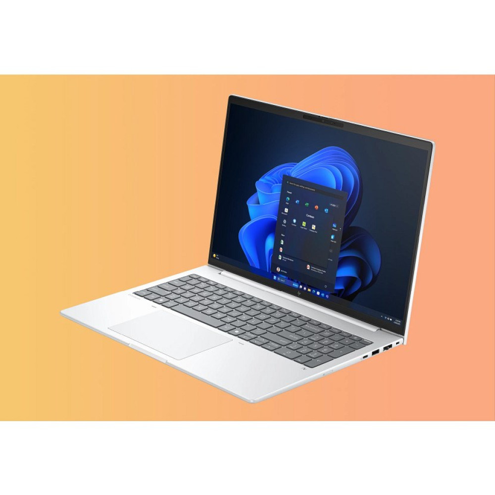 Otwarty srebrny laptop wyświetlający system Windows 11 na ekranie, na pomarańczowym tle.