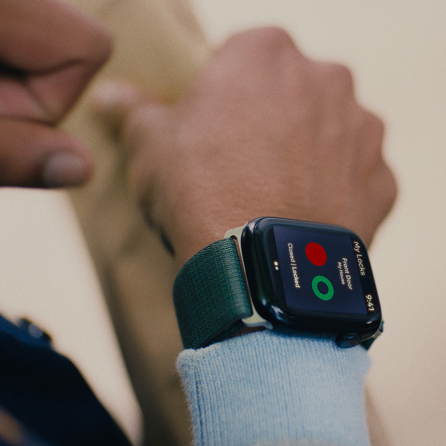 Una persona lleva un smartwatch que muestra una app de cerradura de casa con un icono verde desbloqueado.