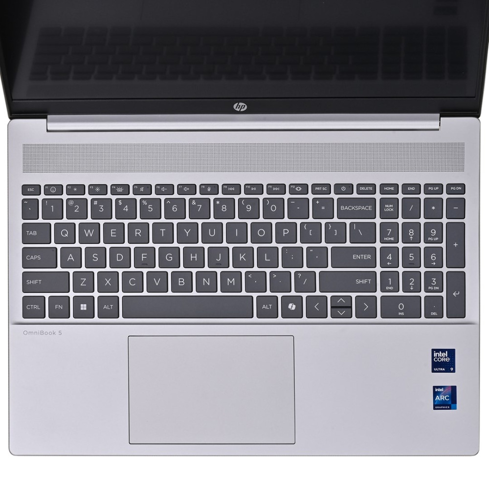 Otwarty srebrny laptop z klawiaturą, touchpadem i naklejkami Intel.