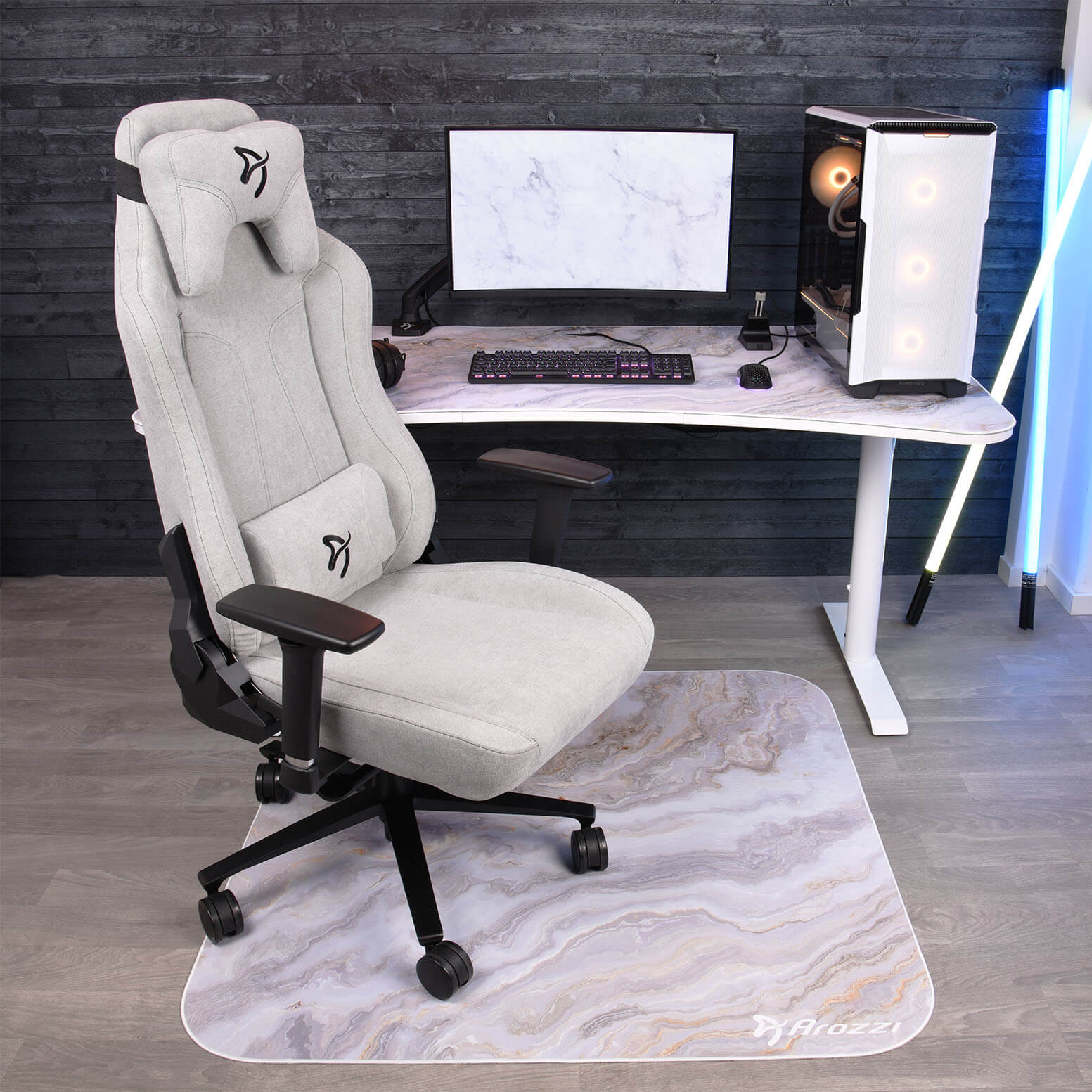 Ein heller Gaming-Stuhl steht vor einem Schreibtisch mit PC und Monitor.