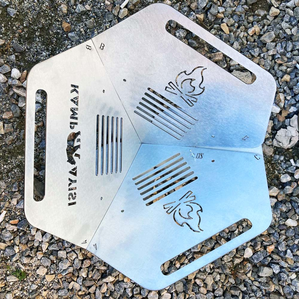 Çakıl üzerinde alev ve hayvan gravürlü altıgen metal ateş çukuru.