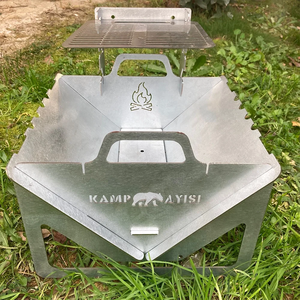 Katlanabilir metal mangal, yeşil çimen üzerinde.