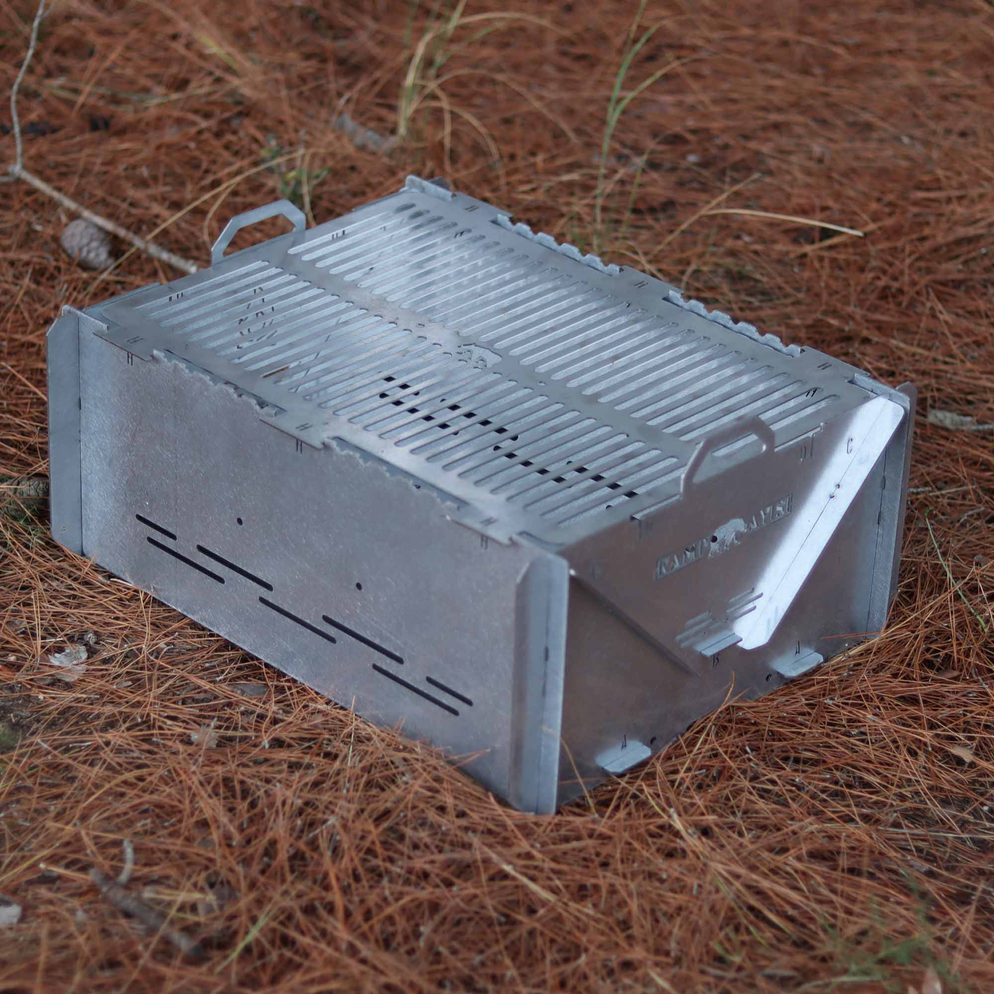 Gümüş metal ızgara, kahverengi çam iğneleri üzerinde duruyor.