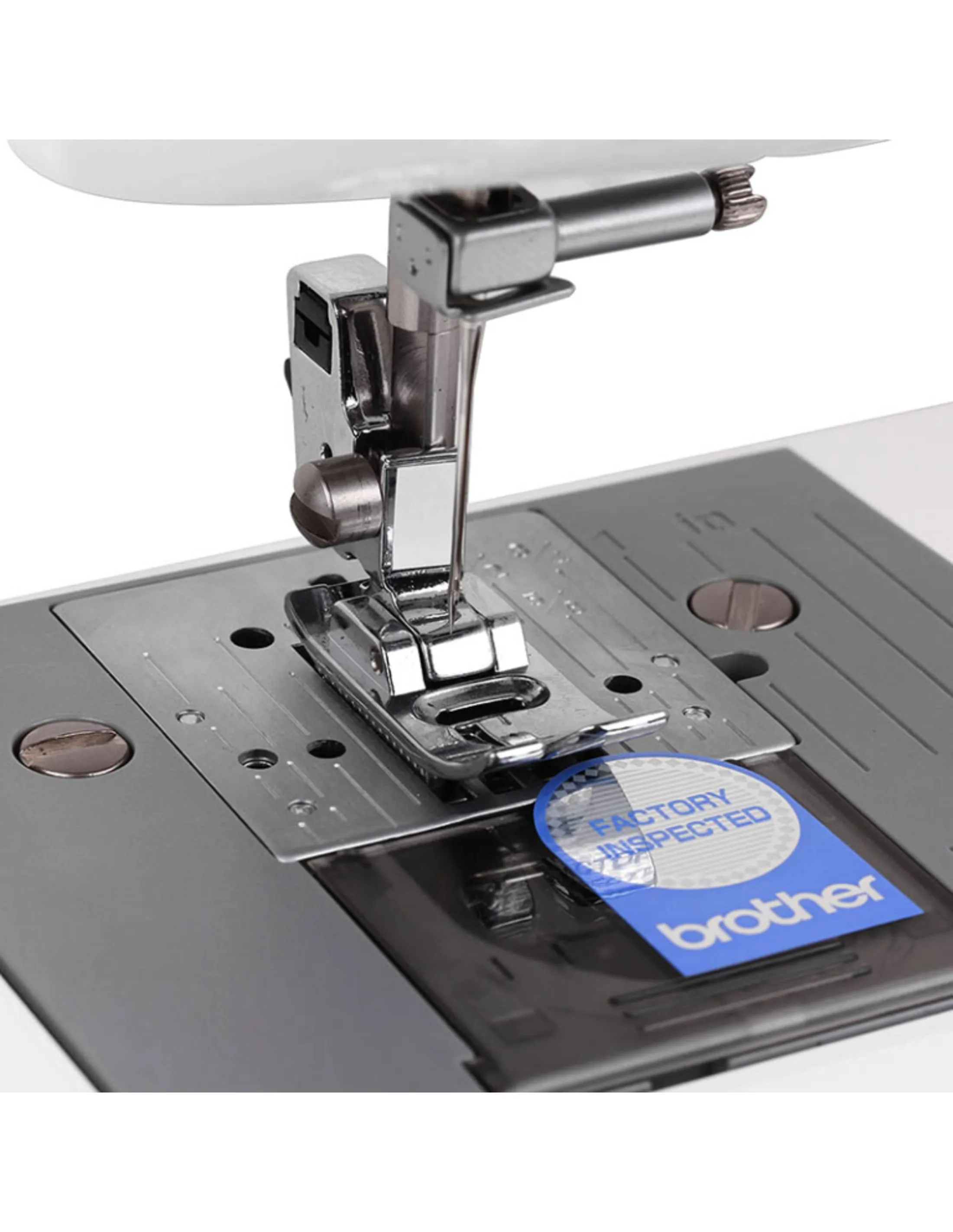 Primer plano de la aguja y el prensatelas de una máquina de coser con una pegatina azul de "Brother".