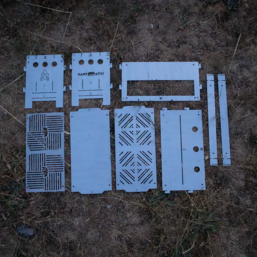 Kamp ocağının sökülmüş metal parçaları kuru otların üzerinde duruyor.