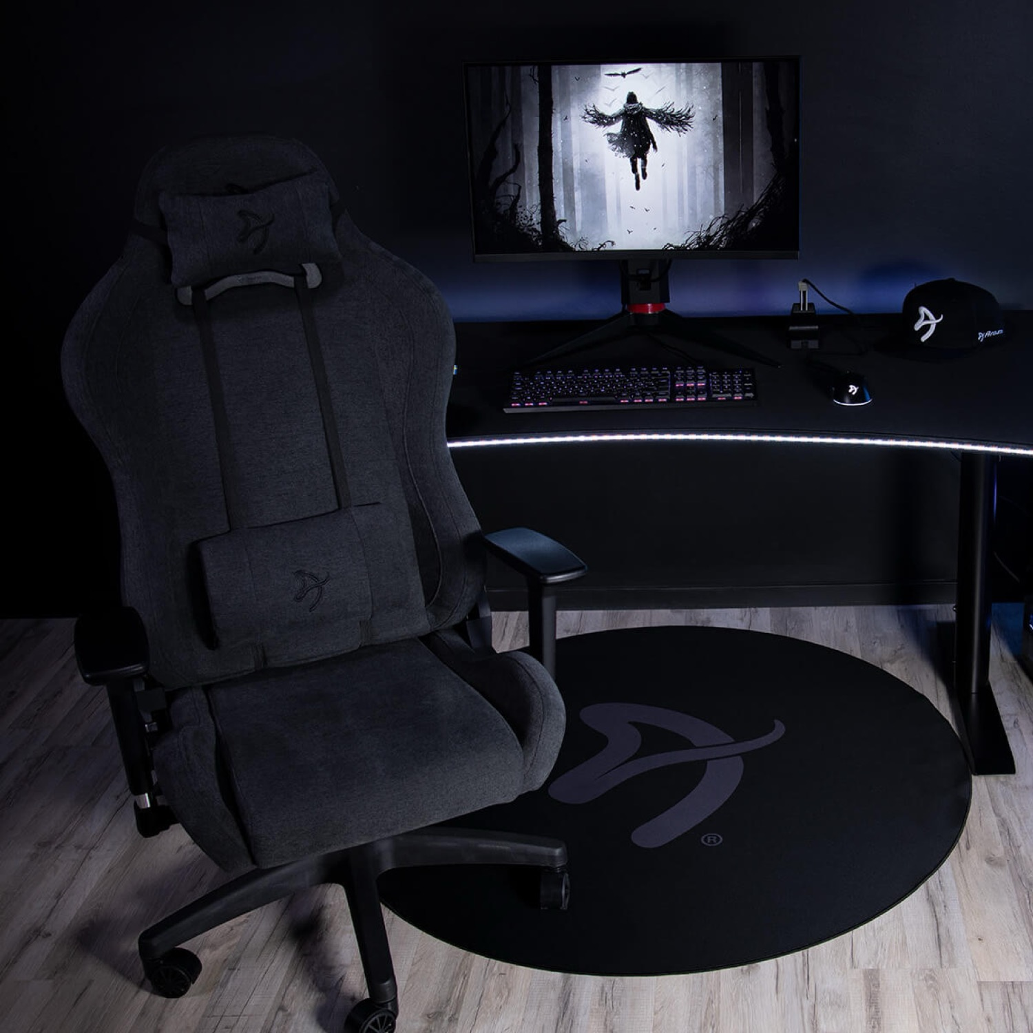 Una sedia da gaming scura di fronte a una scrivania con monitor, tastiera e mouse.