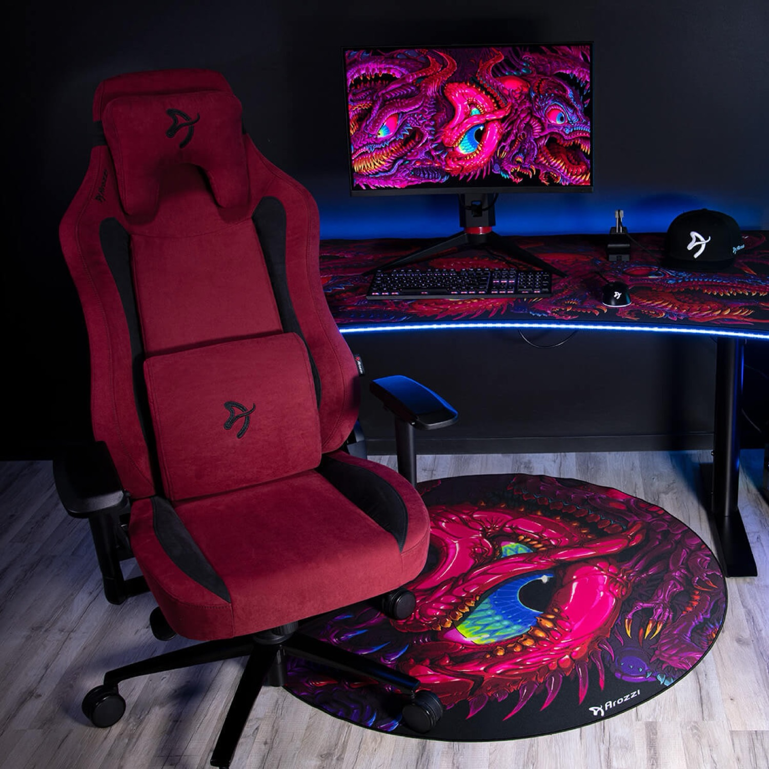 Ein roter Gaming-Stuhl steht neben einem Schreibtisch mit einem Monitor, der ein Drachenbild zeigt.