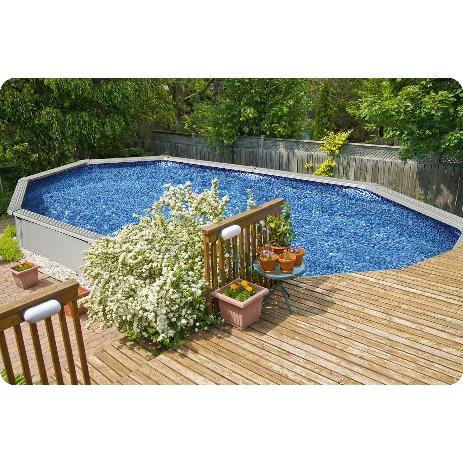 Owalny basen z drewnianym tarasem, kwitnącym krzewem i doniczkami.