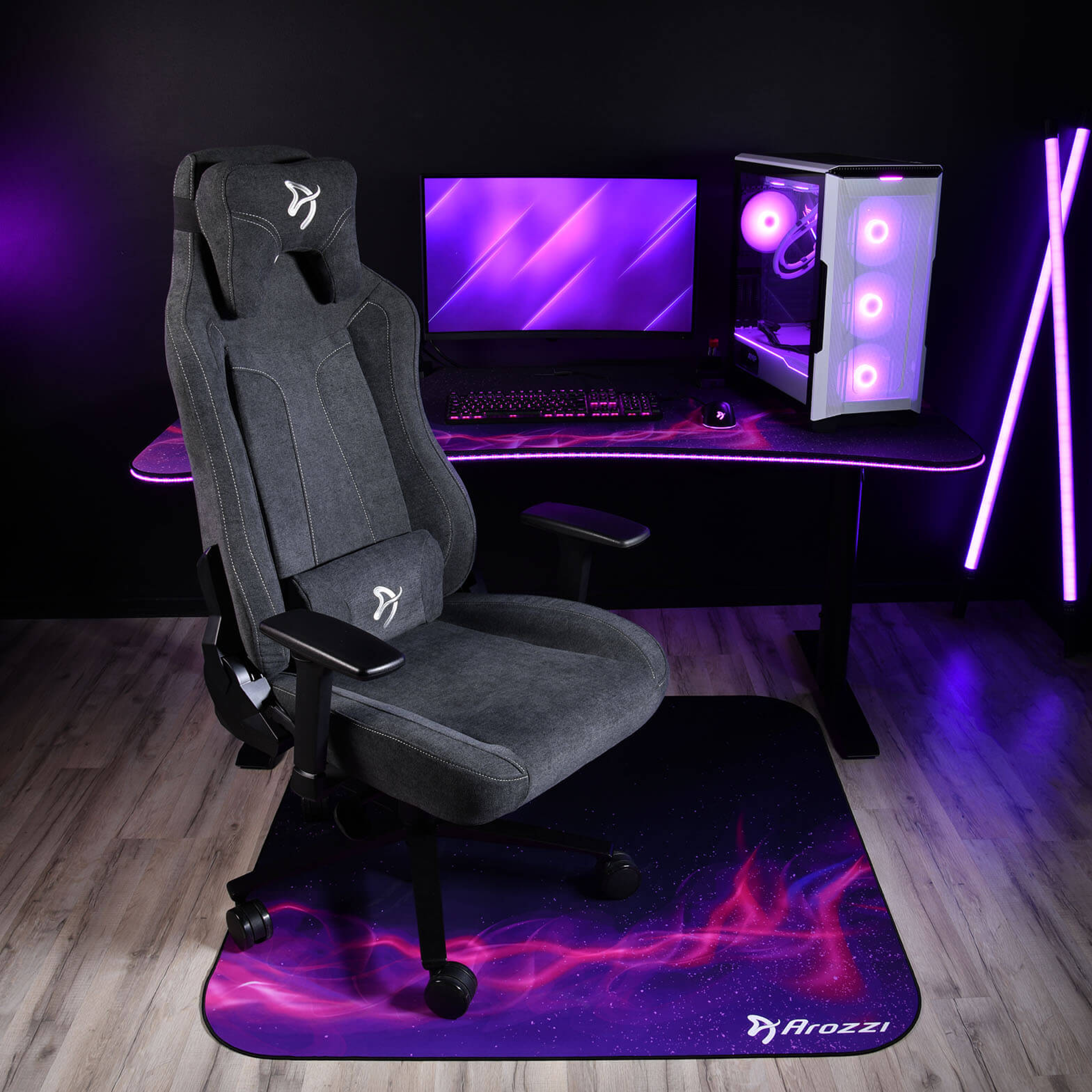 Una sedia da gaming con scrivania, PC, monitor e illuminazione viola.