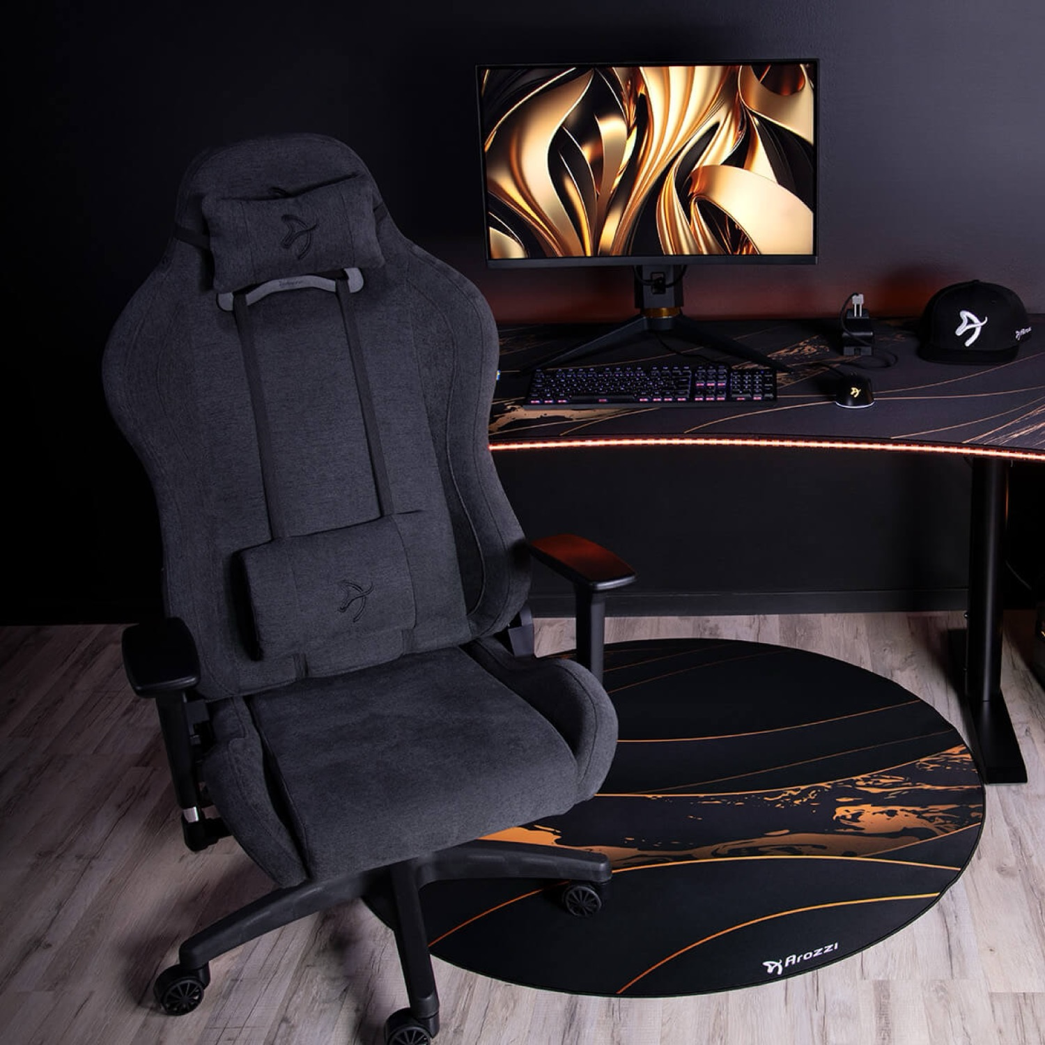 Ein grauer Gaming-Stuhl steht neben einem Schreibtisch mit Monitor, Tastatur und Maus.