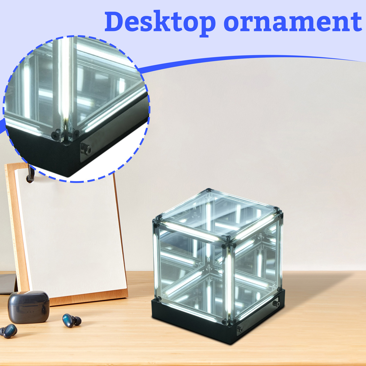 Ein Würfel-Desktop-Ornament mit Lichtern darin, daneben ein Notizblock und Ohrhörer.