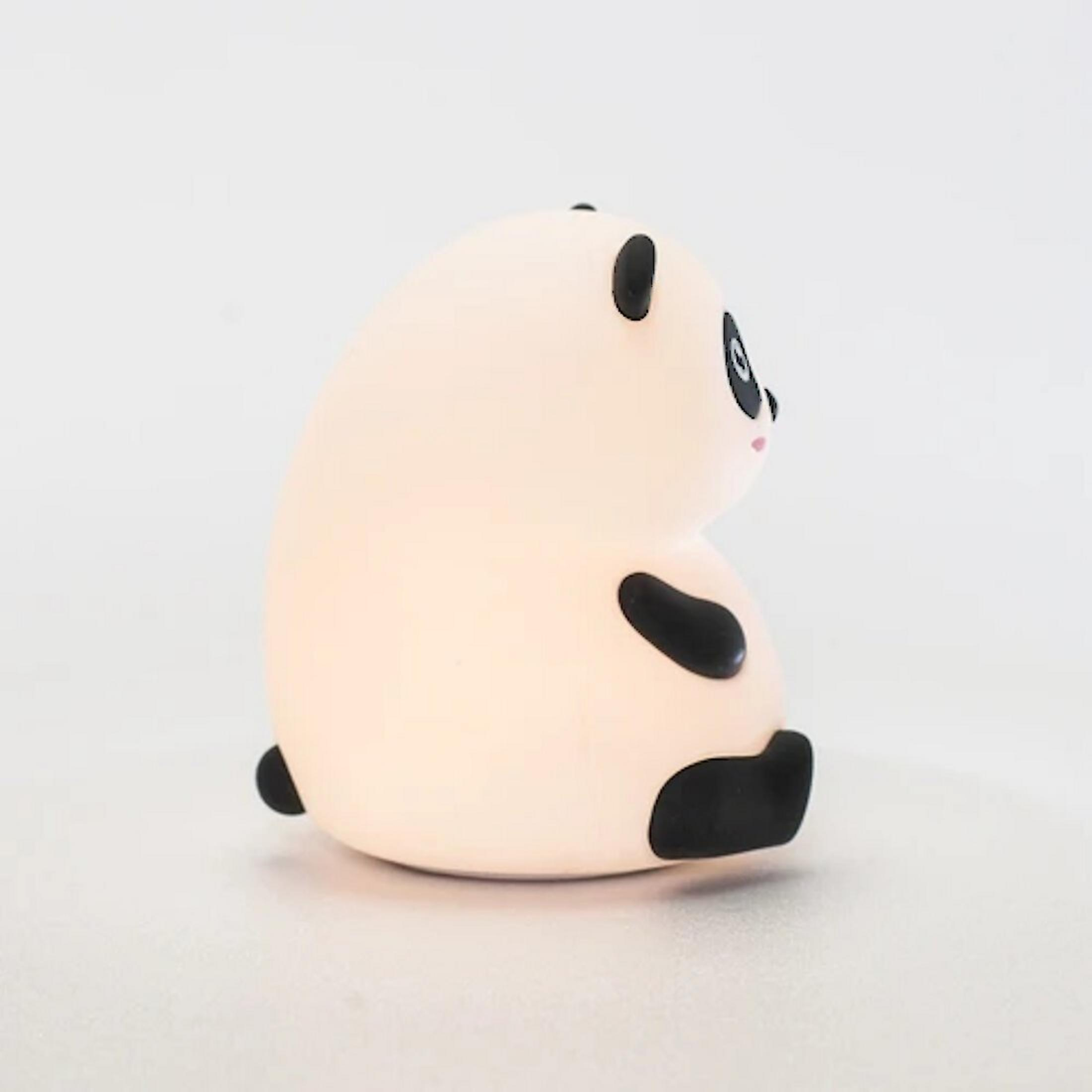 Eine kleine, helle Panda-Figur sitzt seitlich, mit schwarzen Ohren und Flecken.